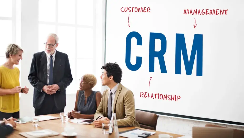 A group of people in a meeting with written text of "CRM" signifying Customer Relation Management