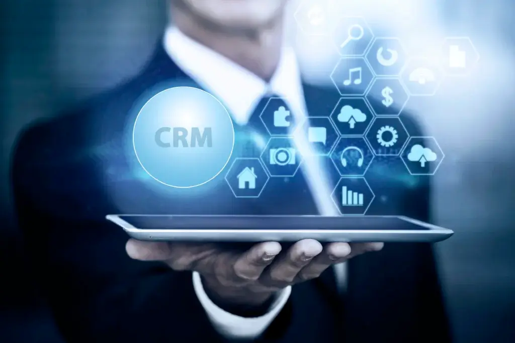 A person holding a tablet bursting mini icons and written text of CRM