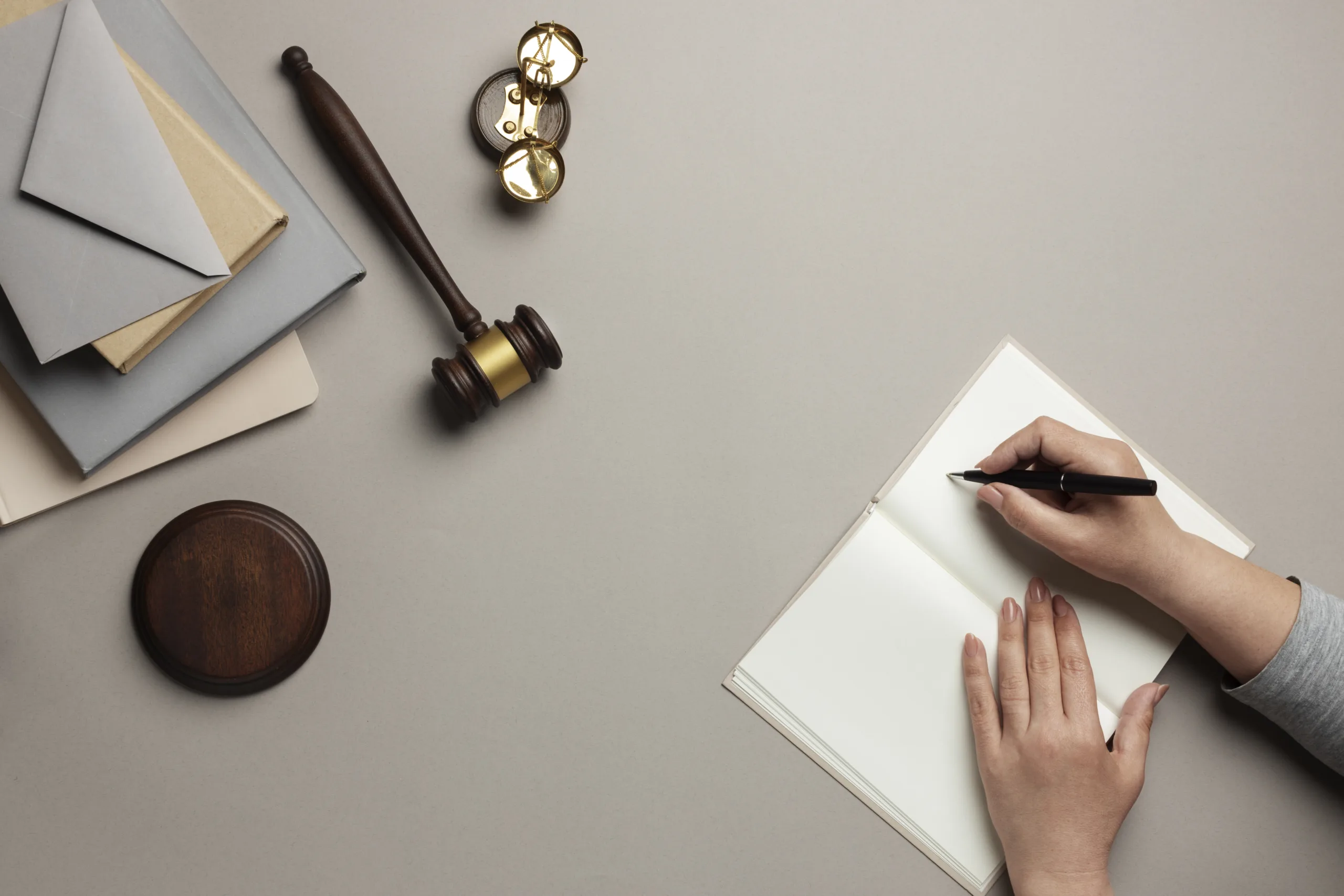A person writing on a book with gavel on the side